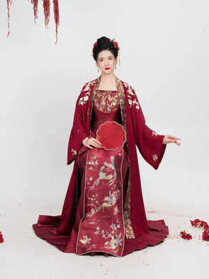Seated model in [Dan Que Acacia] New Chinese Style Red Wedding Dress showcasing intricate floral embroidery and luxurious fabric details.