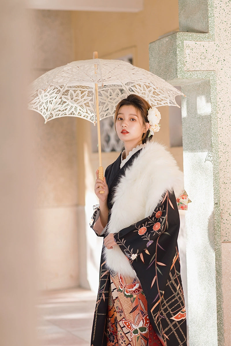 Black kimono with floral designs and white fur shawl, styled with a lace parasol.