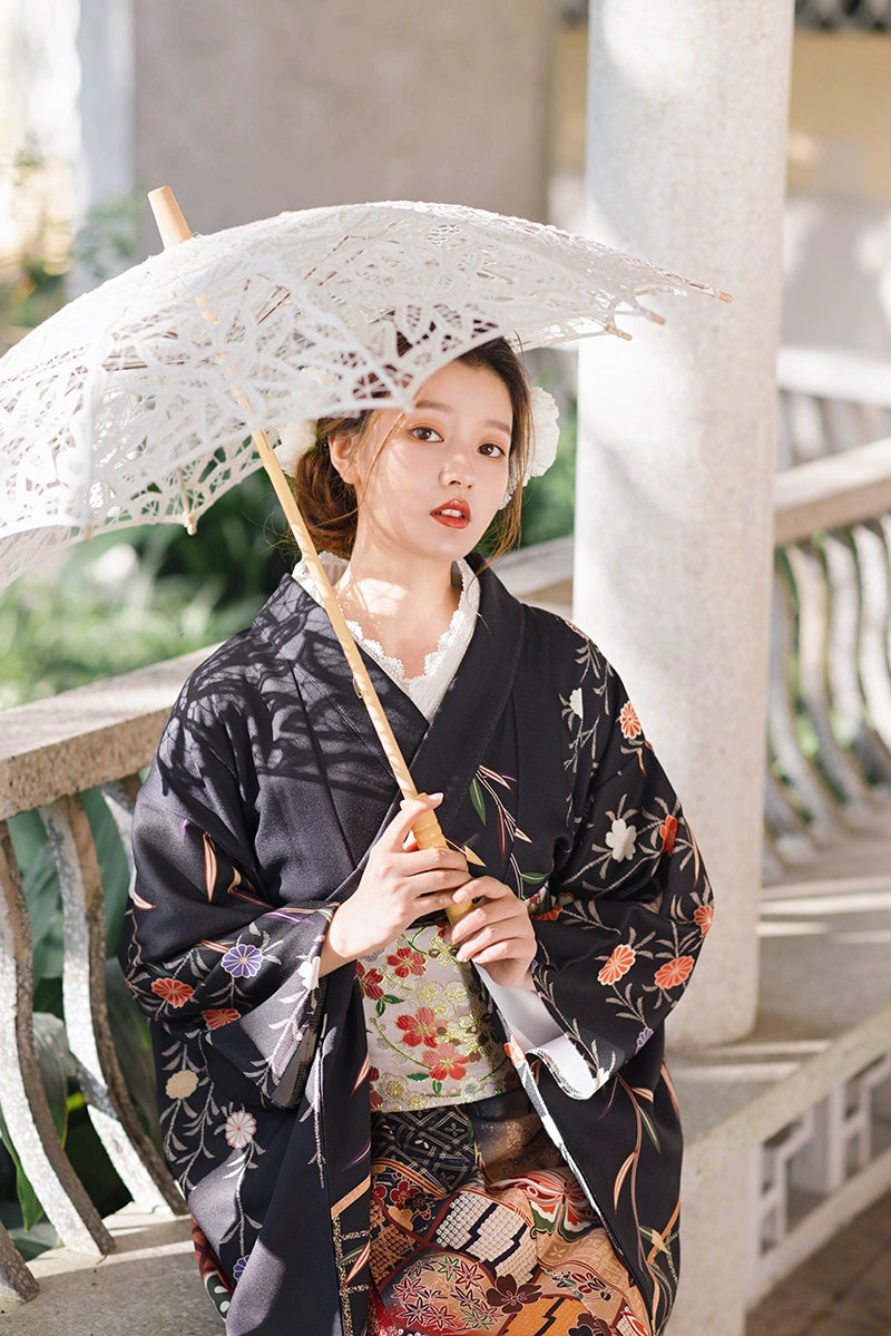 Close-up of a black butterfly kimono with floral patterns, paired with a parasol.