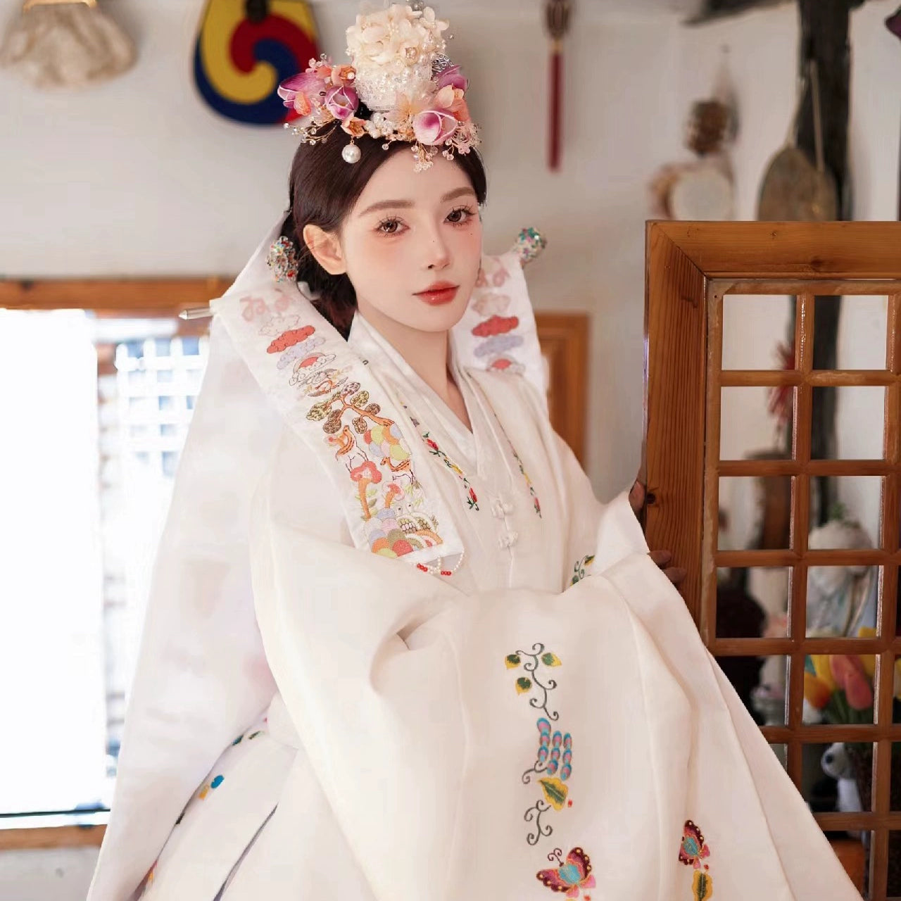 White embroidered Korean wedding hanbok with vibrant floral patterns.