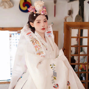 White embroidered Korean wedding hanbok with vibrant floral patterns.