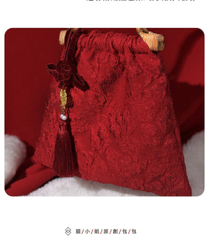 Close-up of a red textured wedding bag with bamboo handle and decorative tassel, designed for bridal and festive events.