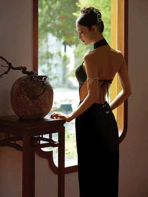 Side view of a black fishtail cheongsam dress with an open back design, styled with elegant accessories and a chic updo.