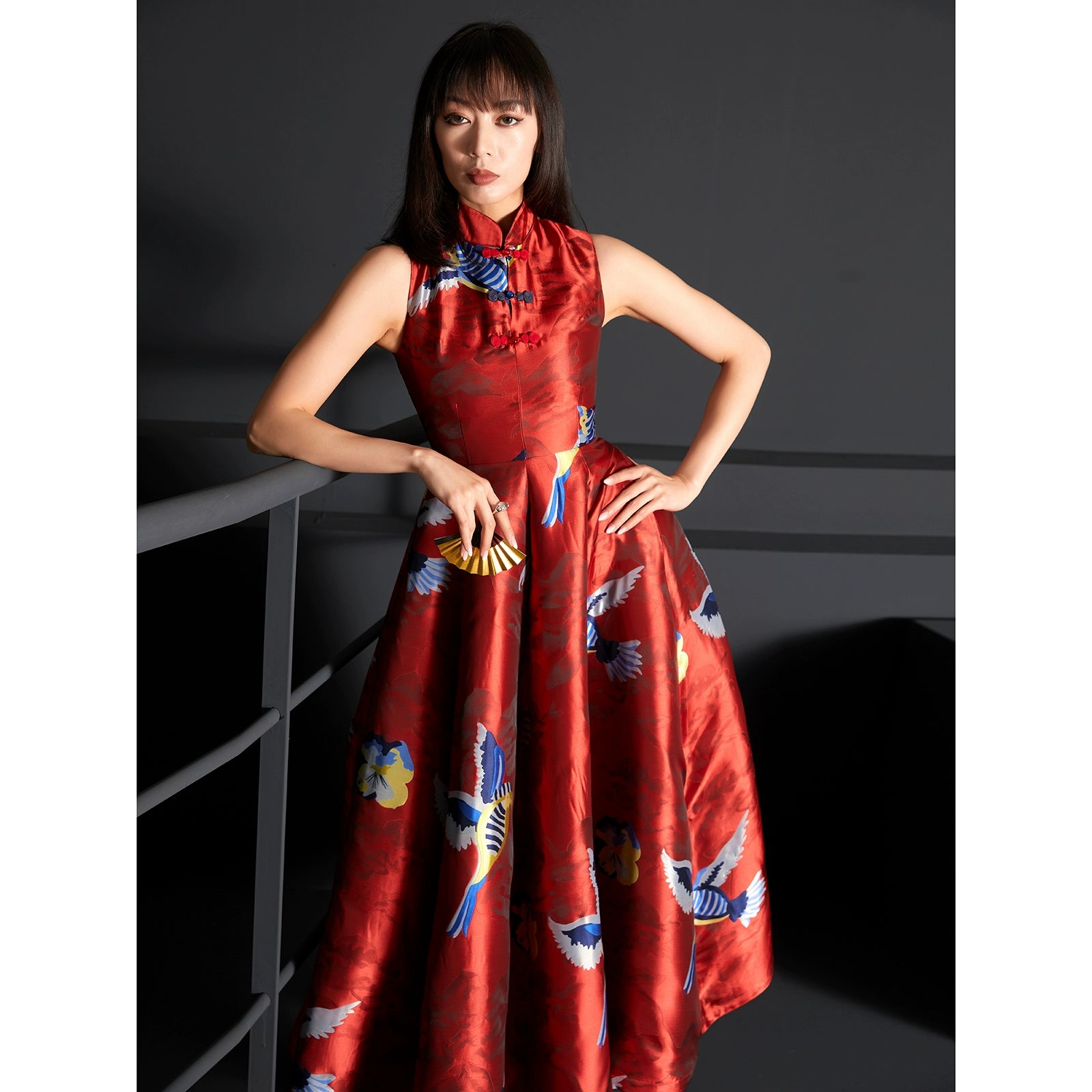 Model posing in a red brocade jacquard cheongsam dress with vibrant patterns.