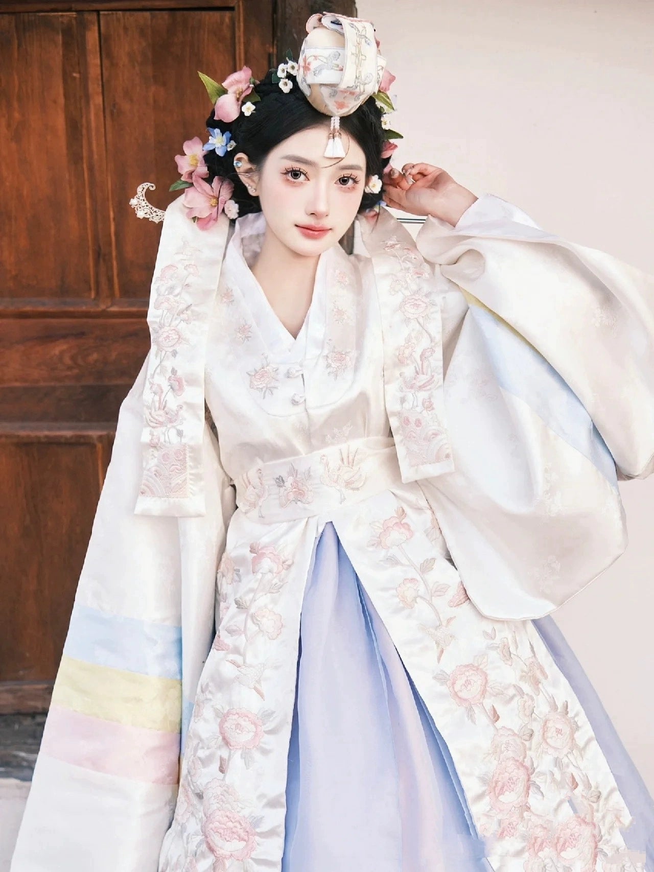 Bride in a Muzhi white Korean embroidered wedding dress, adorned with intricate floral embroidery and pastel hues for a regal wedding appearance.