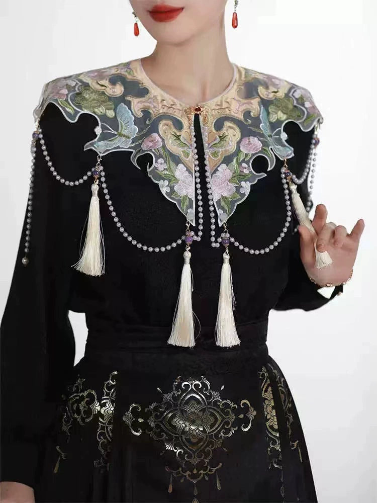 Black cheongsam dress with embroidered floral collar and tassel details, styled for engagement or formal events.