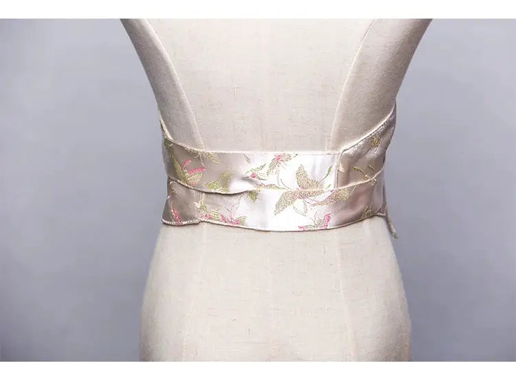 Rear view of a white brocade kimono belt seal with pink and green floral embroidery, elegantly styled on a mannequin.