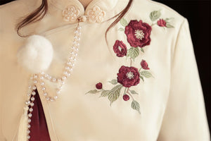 Close-up of cream top with floral embroidery and pearl tassel details, part of the Camellia Lolita cheongsam dress.