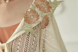 Floral applique detail on the ivory capelet collar