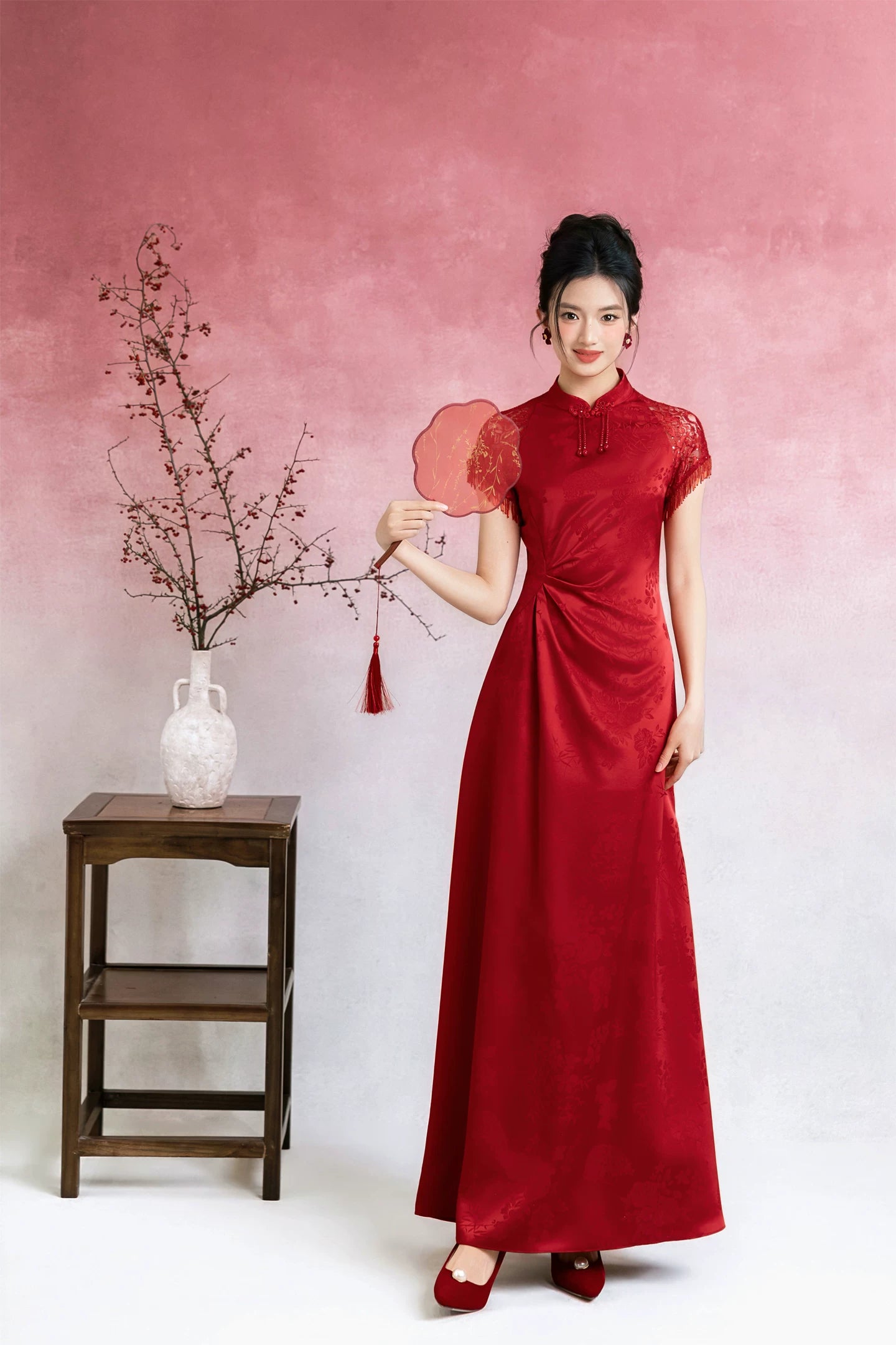 Full-length red bridal cheongsam against pink studio backdrop