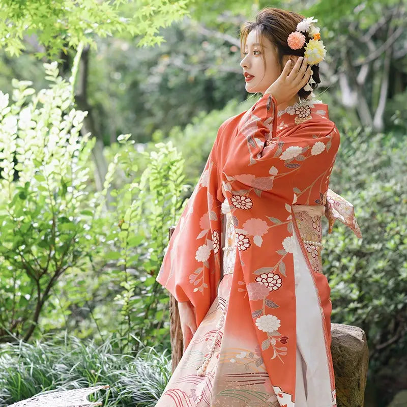 Japanese kimono in orange with chrysanthemum patterns, styled with floral hair accessories, ideal for travel and photography.