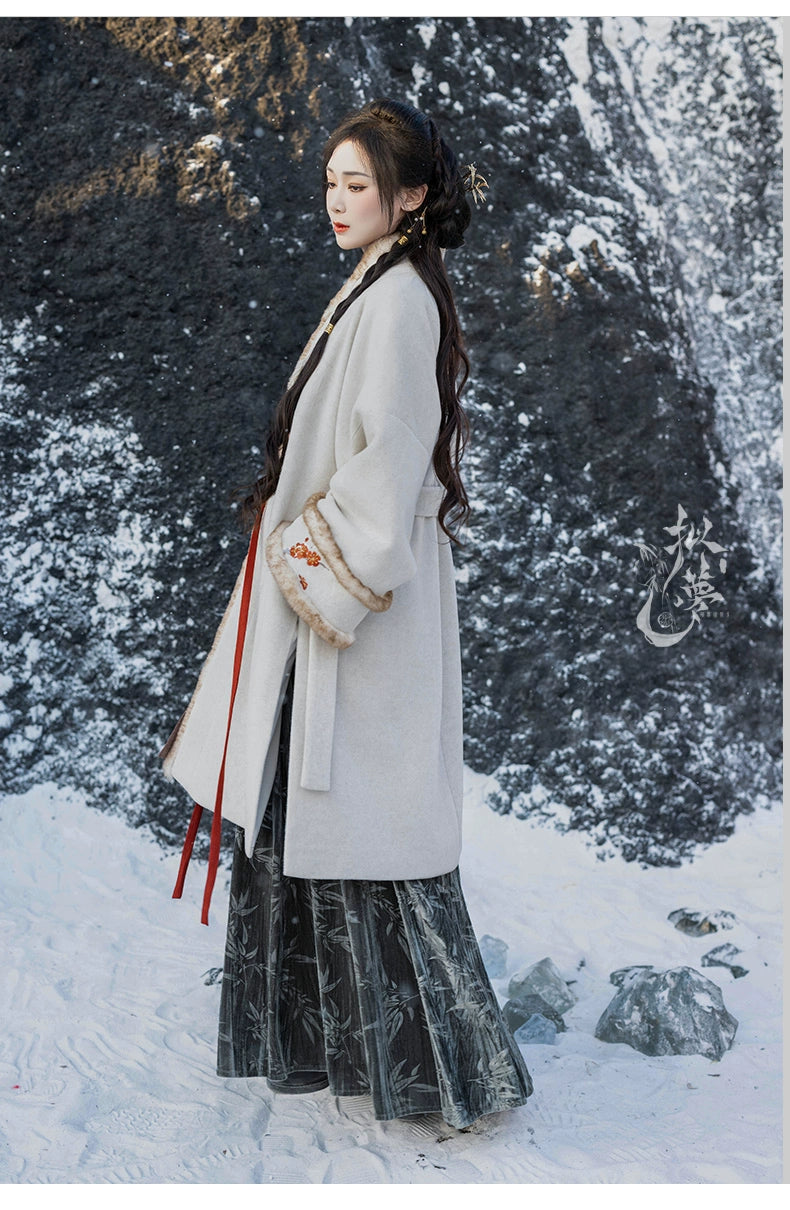 Side view of white woolen Hanfu coat with floral embroidery and faux fur cuffs, paired with a green pleated skirt for winter elegance.