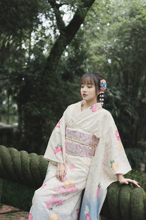 Model in a white floral kimono, leaning on a moss-covered bridge in a serene forest.