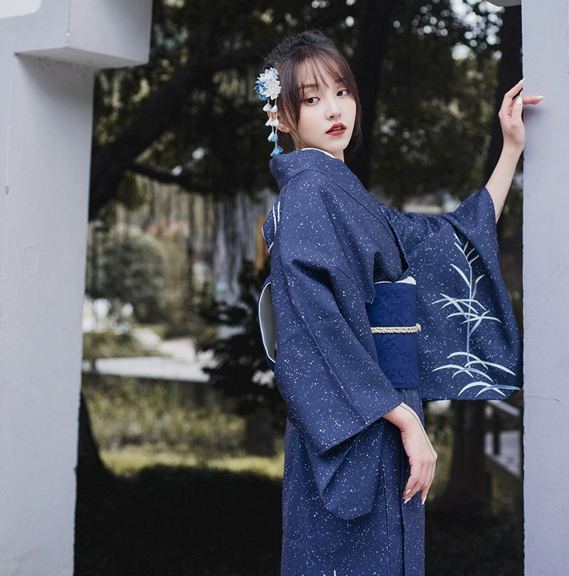 Elegant blue Japanese kimono yukata with floral patterns, worn outdoors.