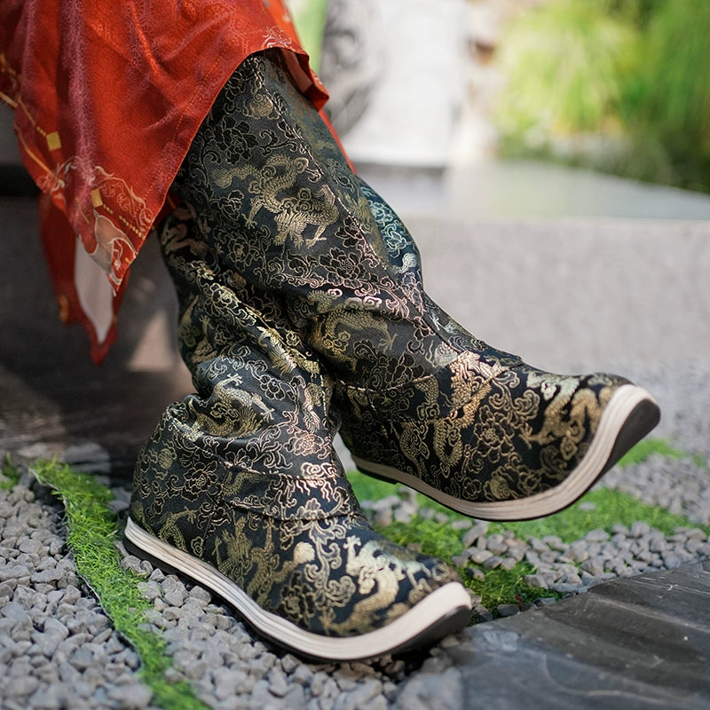 Close-up of black and gold Dragon boots with intricate embroidery, styled with a red Hanfu robe, highlighting traditional Ming design.