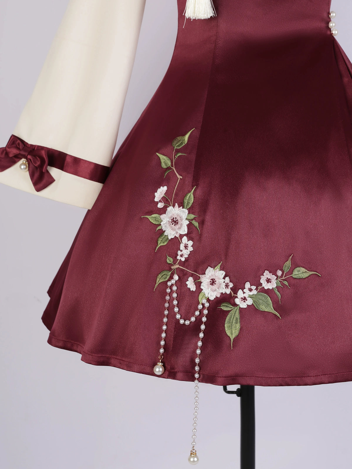 Detailed view of burgundy skirt with floral embroidery and pearl tassel embellishments from the Camellia Lolita cheongsam.