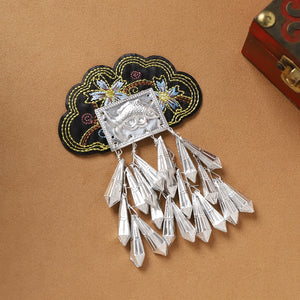Guizhou Miao fridge magnet with black floral embroidery and silver arrowhead fringe, handmade cultural kitchen accessory.