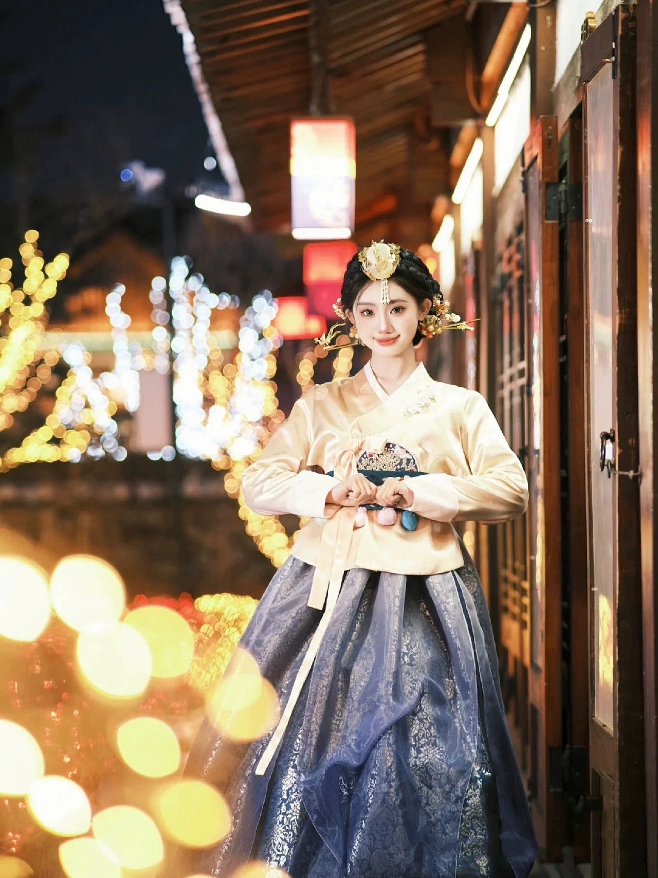 Traditional Korean Hanbok in blue and gold, worn in a picturesque setting, highlighting its timeless beauty and cultural heritage.