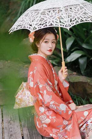 Detailed view of a retro orange kimono with chrysanthemum patterns, styled with a lace parasol and floral hair accessory.