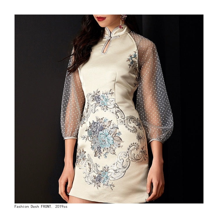 Close-up of white cheongsam with floral embroidery and elegant sheer sleeves.