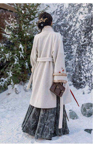 Back view of white woolen Hanfu coat with a belted design, floral embroidery, and faux fur cuffs, paired with a green skirt.