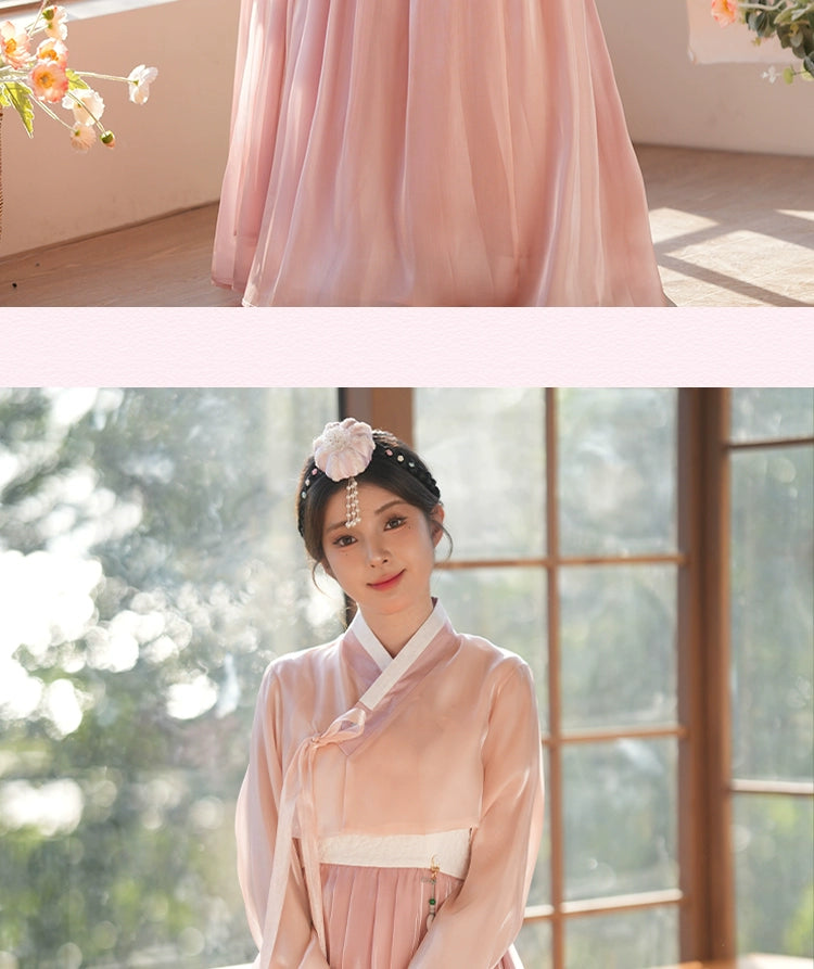 Woman in a pink hanbok dress, standing in a sunlit room with floral decor. A beautiful blend of tradition and modern elegance.