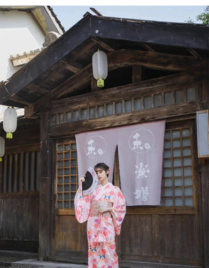 Decorative Japanese fan with cherry blossom design, paired with a pink artificial flower and a white accessory ribbon.