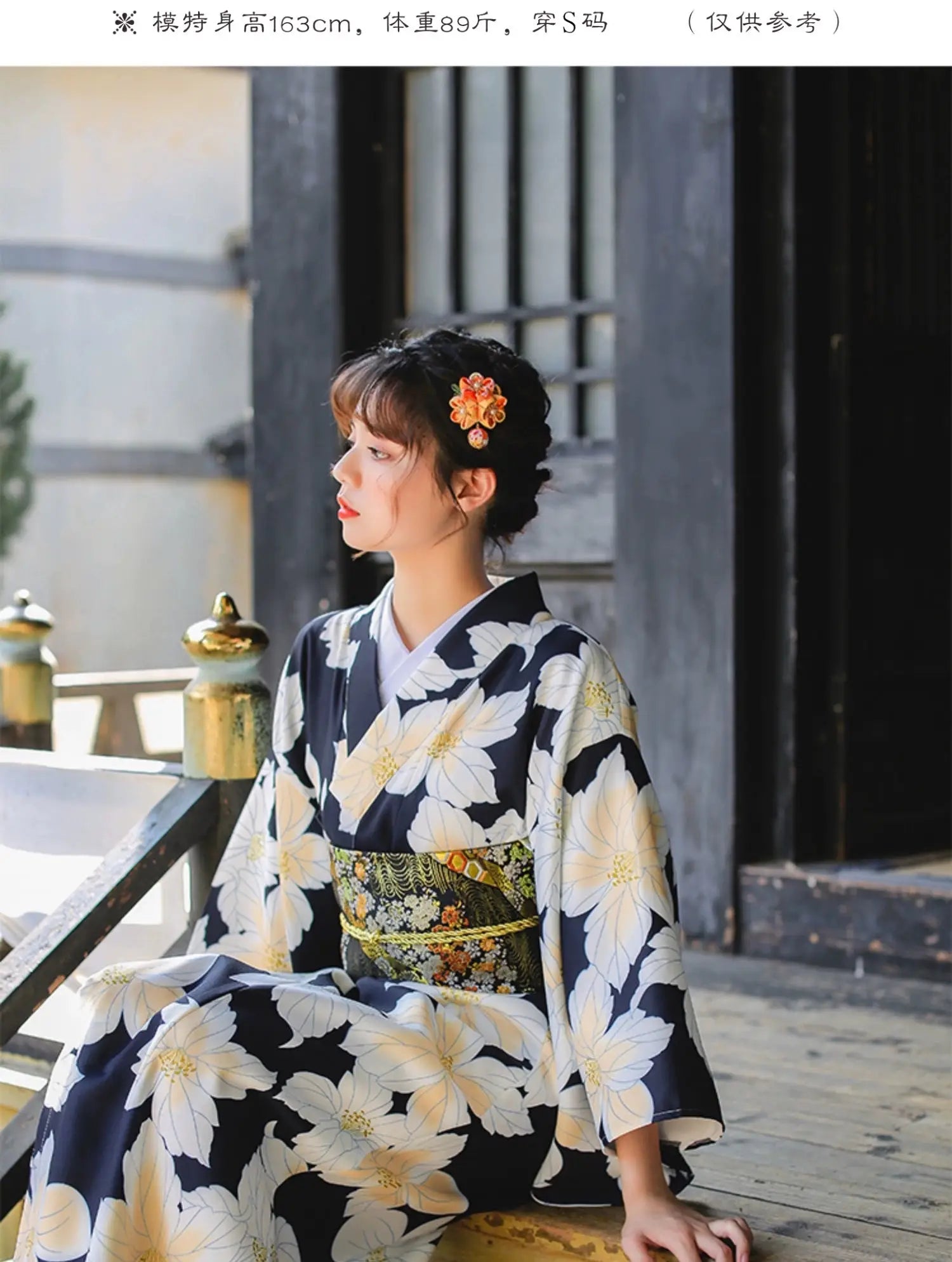 Woman wearing a Japanese kimono dress with a floral pattern, seated outdoors, styled with a traditional obi belt for a festive look.