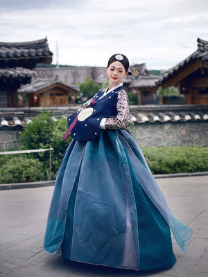 Elegant Korean women's navy blue bronzing hanbok court dress with intricate gold embroidery, worn in a traditional setting. Perfect for special occasions.