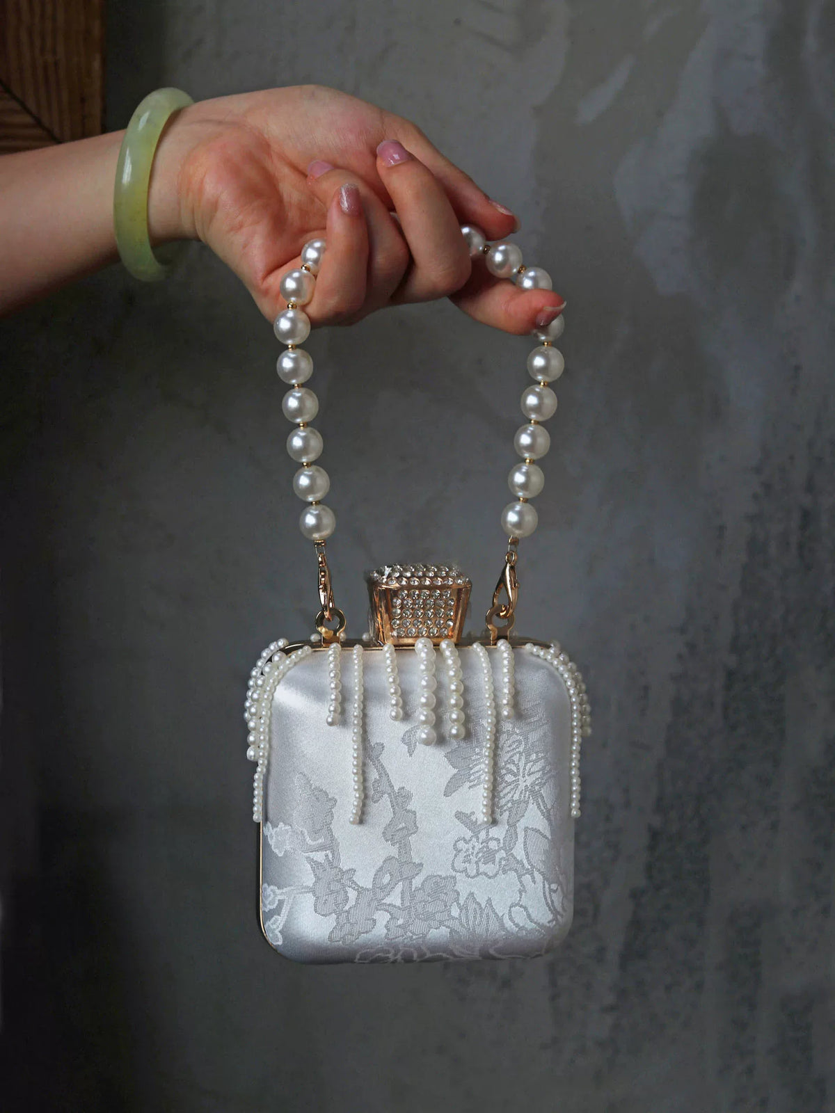 Mini square handbag carried by its beaded handle