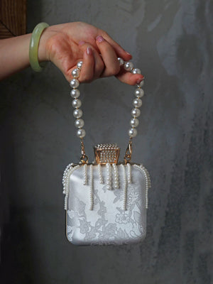 Mini square handbag carried by its beaded handle