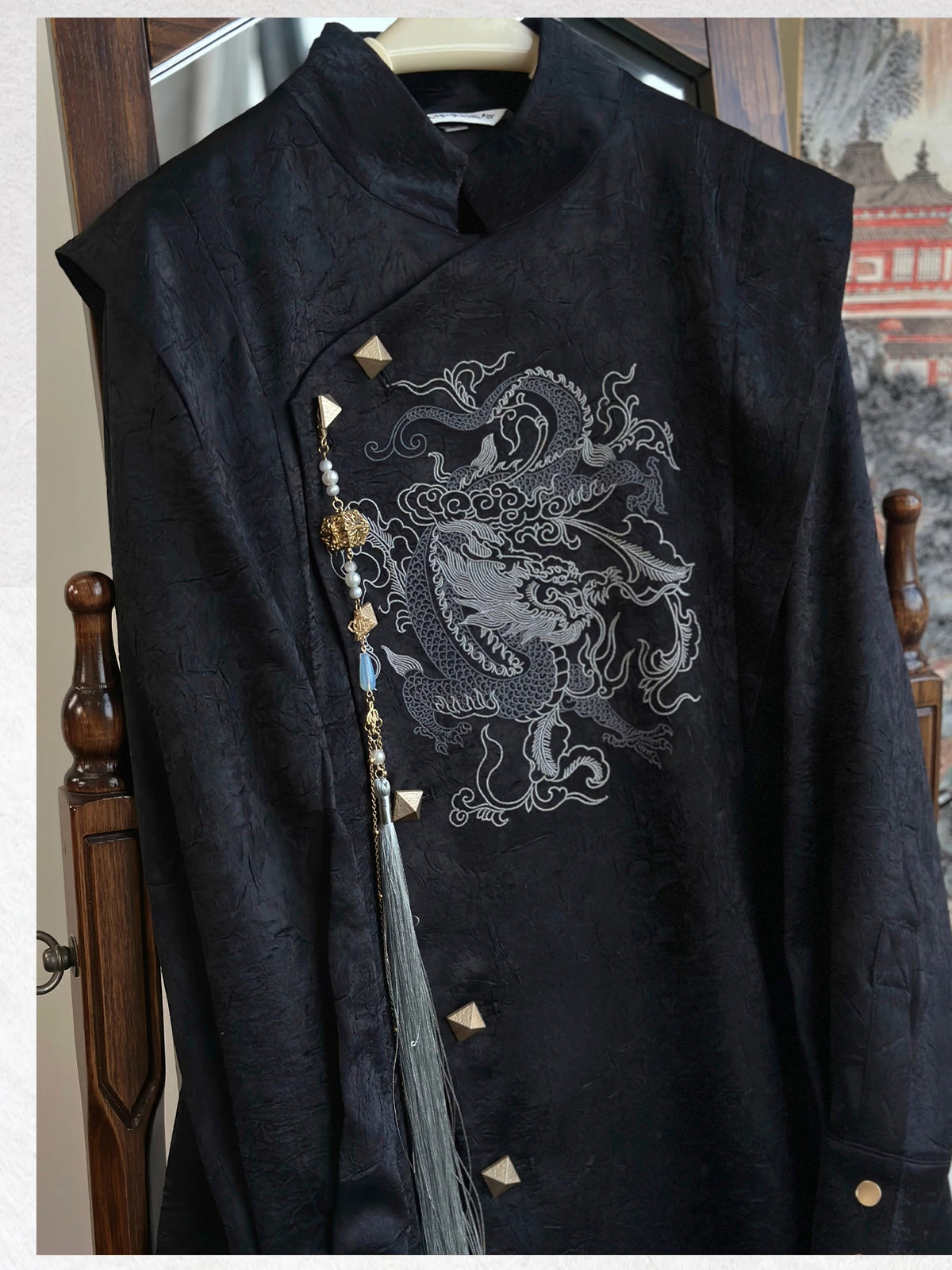 Black dragon embroidery coat on a hanger showing textured fabric, gold-tone buttons and a detachable tassel