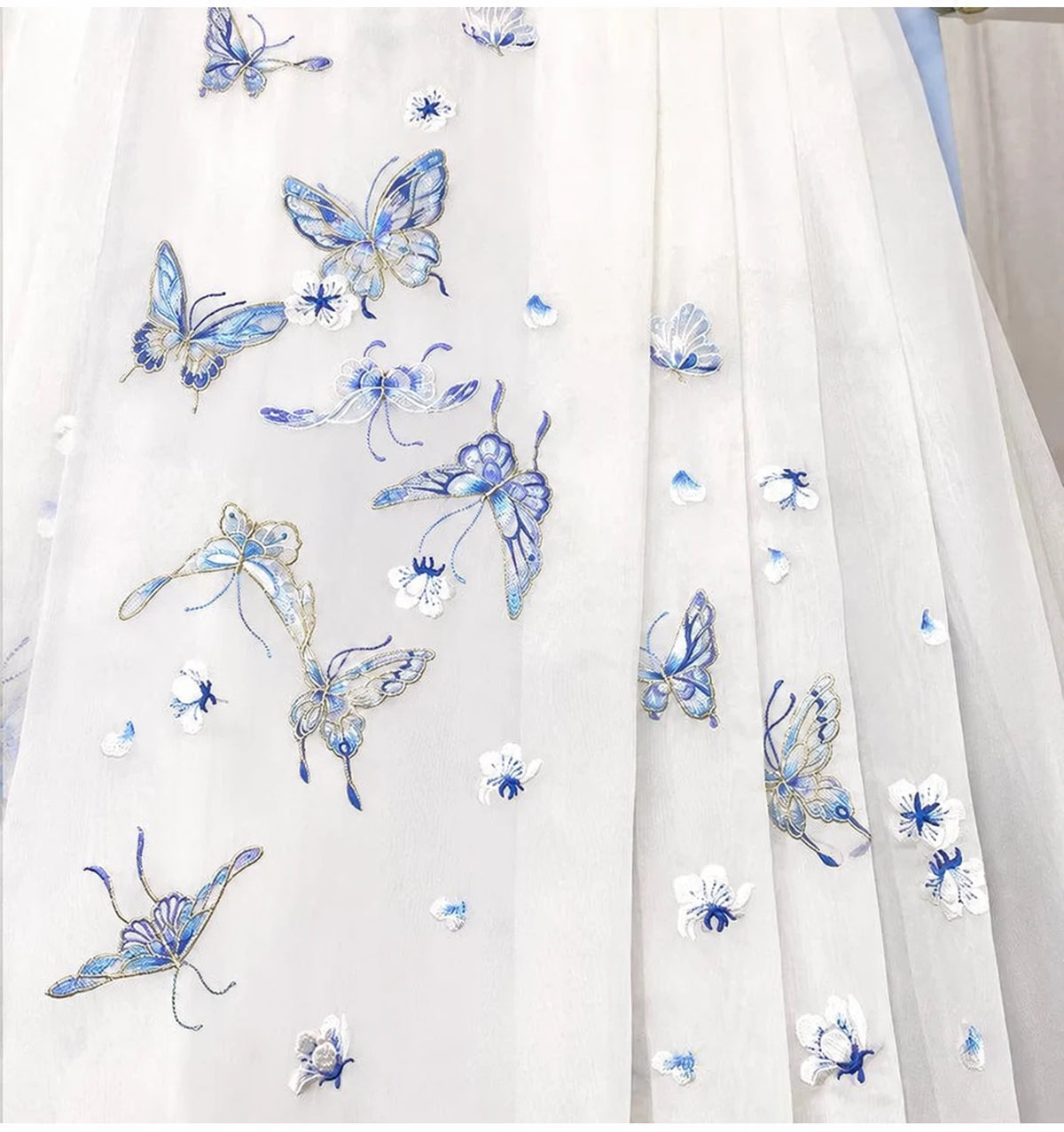 Blue butterflies and small floral embroidery scattered across the sheer white mamian skirt fabric