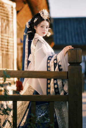 Three-quarter view of white and navy royal court Hanbok by a wooden railing