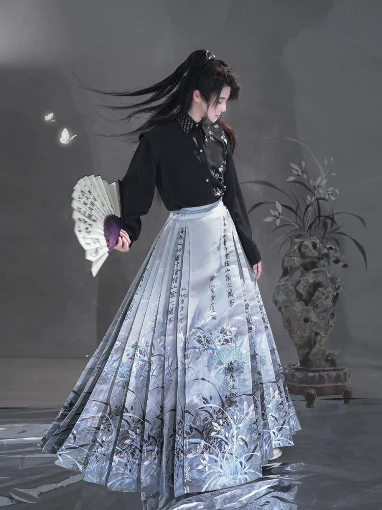 Sky blue Clivia mamian skirt styled with a black shirt, full-length view of botanical motifs and wide pleats.