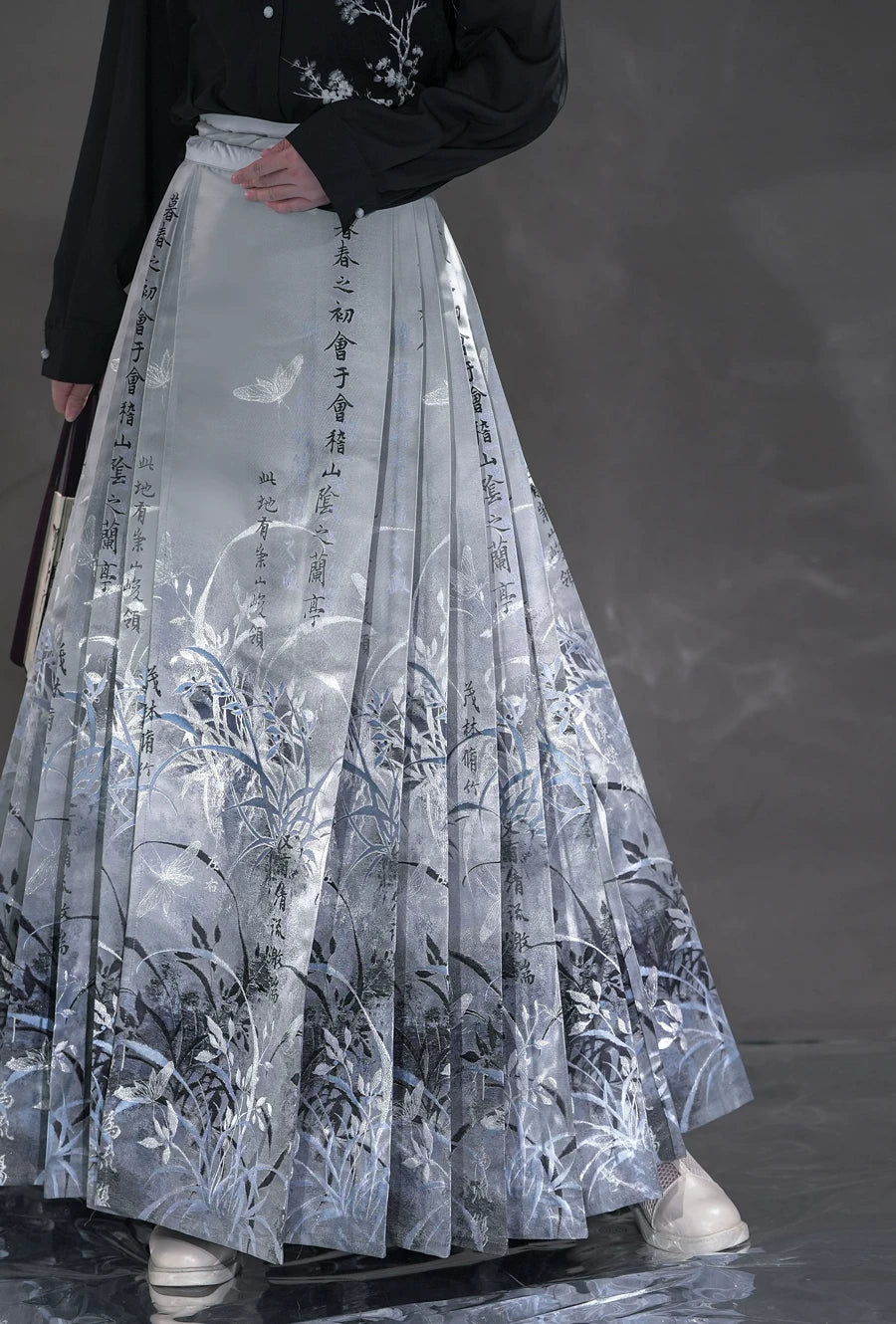 Long sky blue Clivia mamian skirt front panel with floral motifs and vertical script.