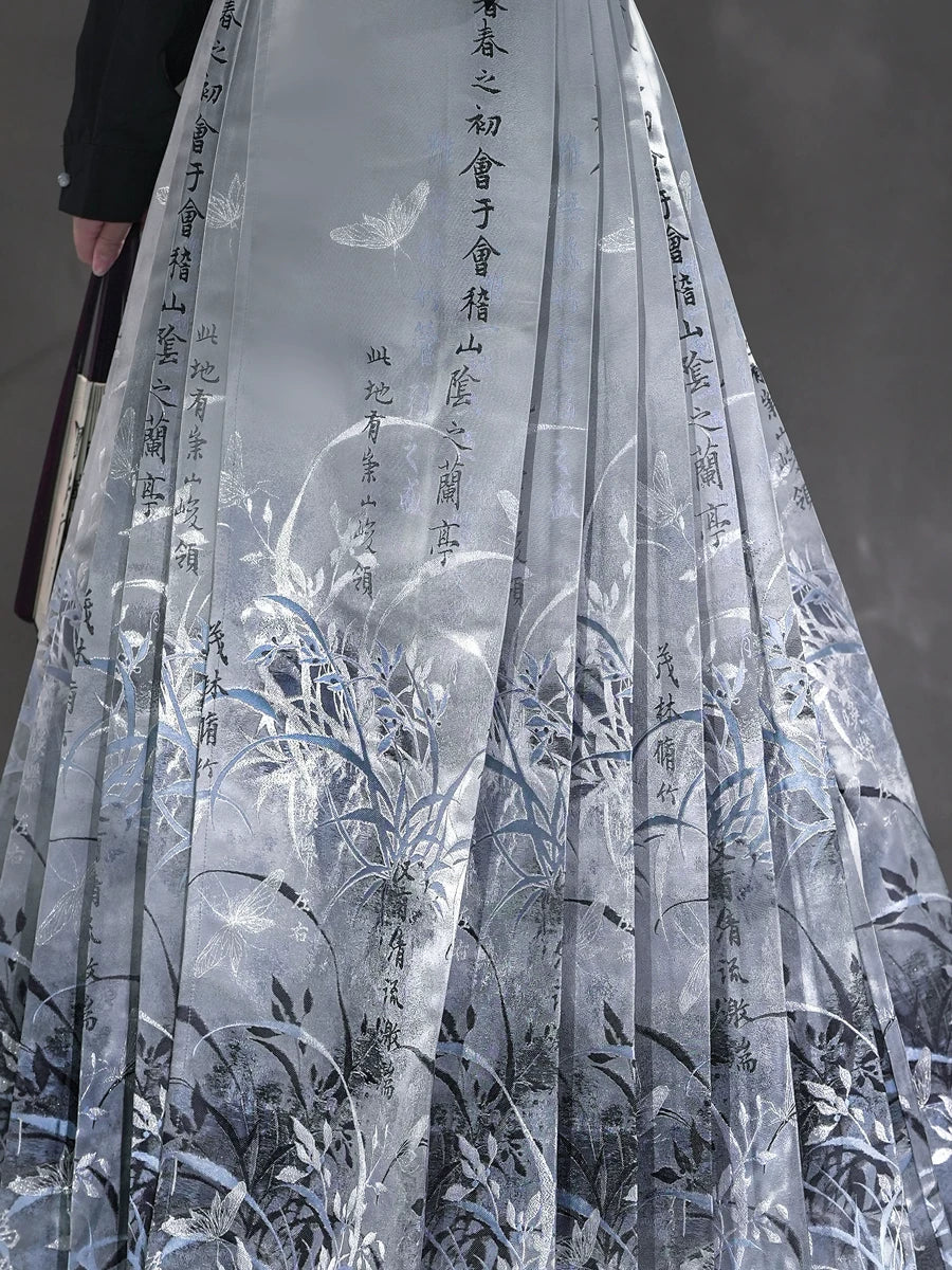 Close view of the Clivia skirt front panel with vertical calligraphy and pale botanical motifs.
