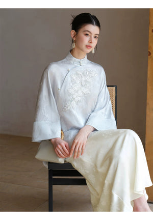 Close product view of the Cloud-Mist Blue embroidered satin top and skirt, focused on its Chinese-inspired design details.