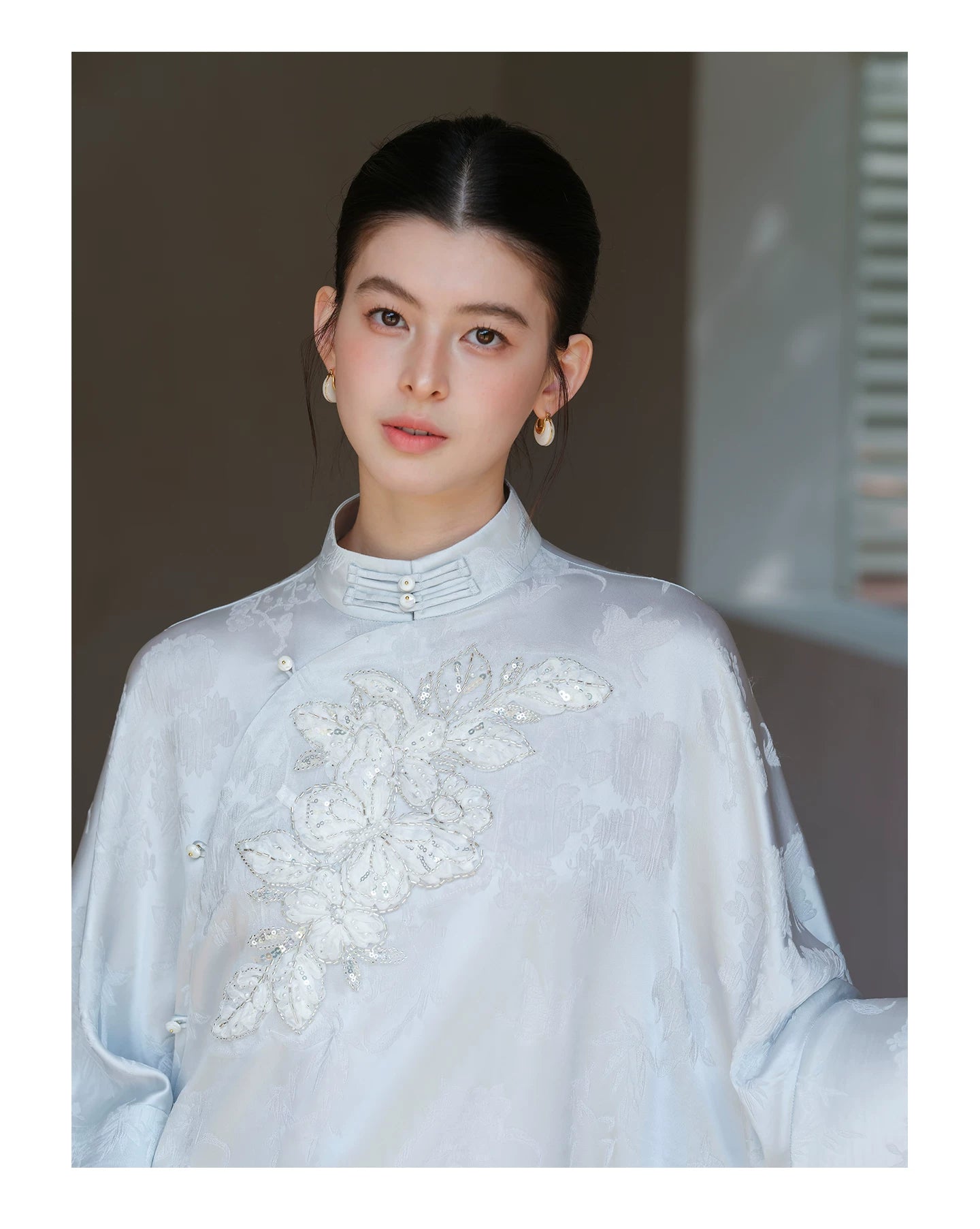 Additional styling view of the Cloud-Mist Blue embroidered satin top and skirt, showing the garment's shape, texture and finish.