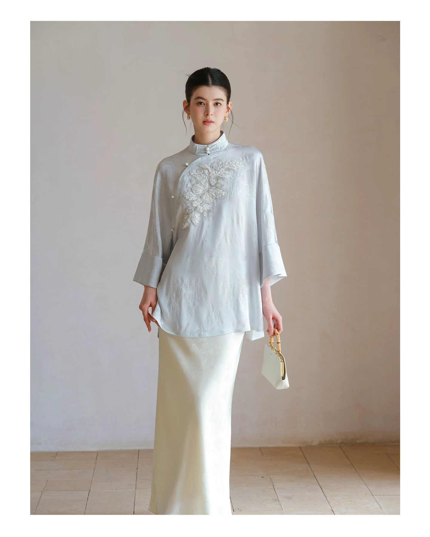 Cloud-Mist Blue embroidered satin top and skirt styled to show its fit and drape, including floral bead embroidery, stand collar and fluid satin silhouette.
