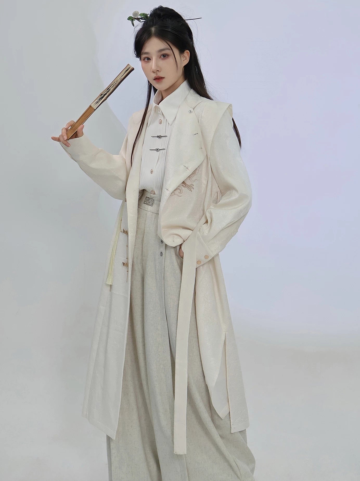 Beige dragon embroidery long coat styled open over light separates, showing the long silhouette and stand-collar neckline of this unisex Chinese style layer.
