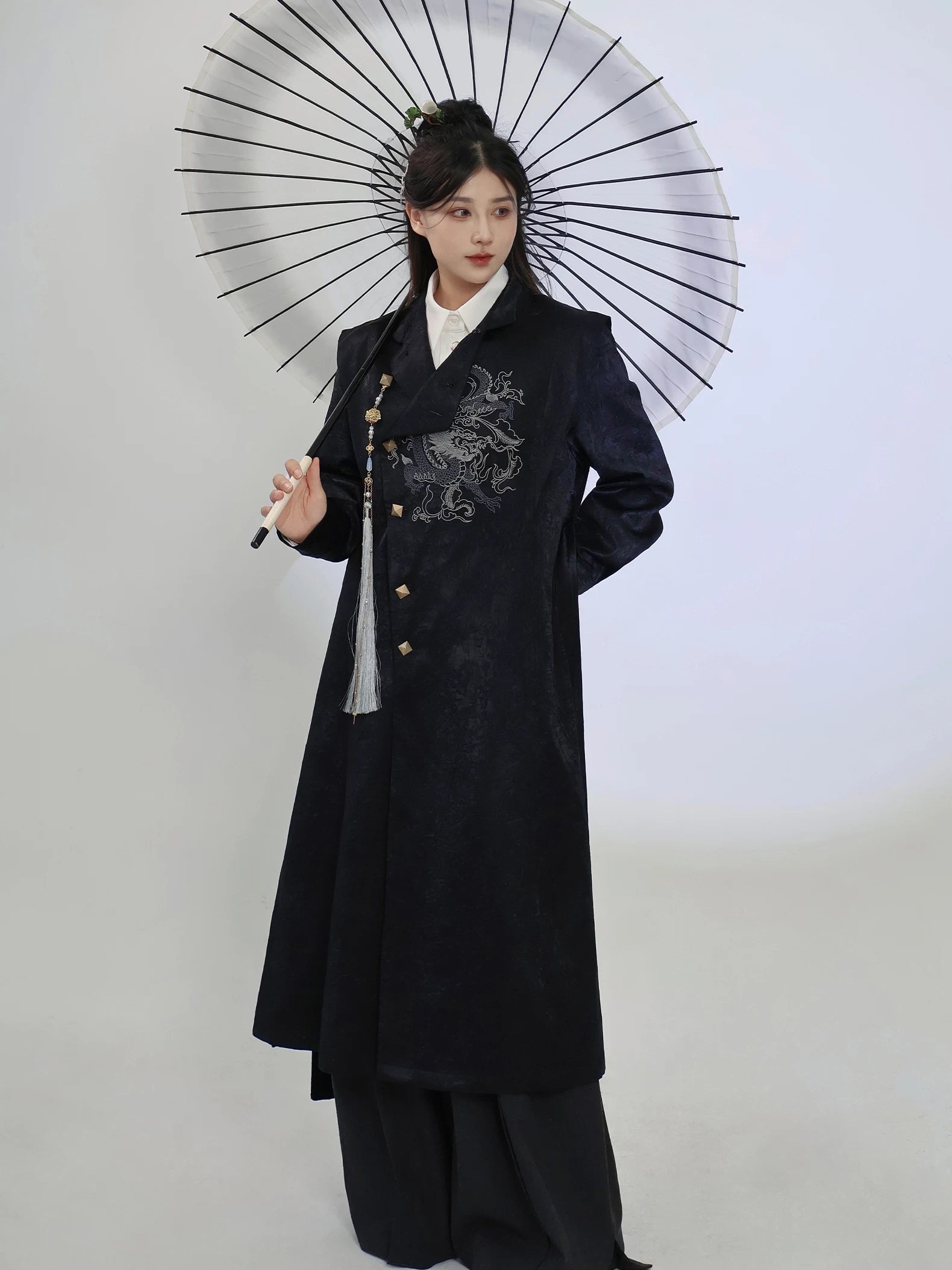 Front view of the black New Chinese style long coat, showing the dragon embroidery, stand collar and flowing longline cut with wide-leg trousers.