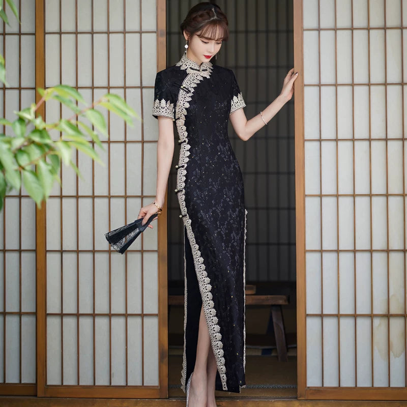 Full-length front view of the black lace qipao with pale trim tracing the collar and side slit