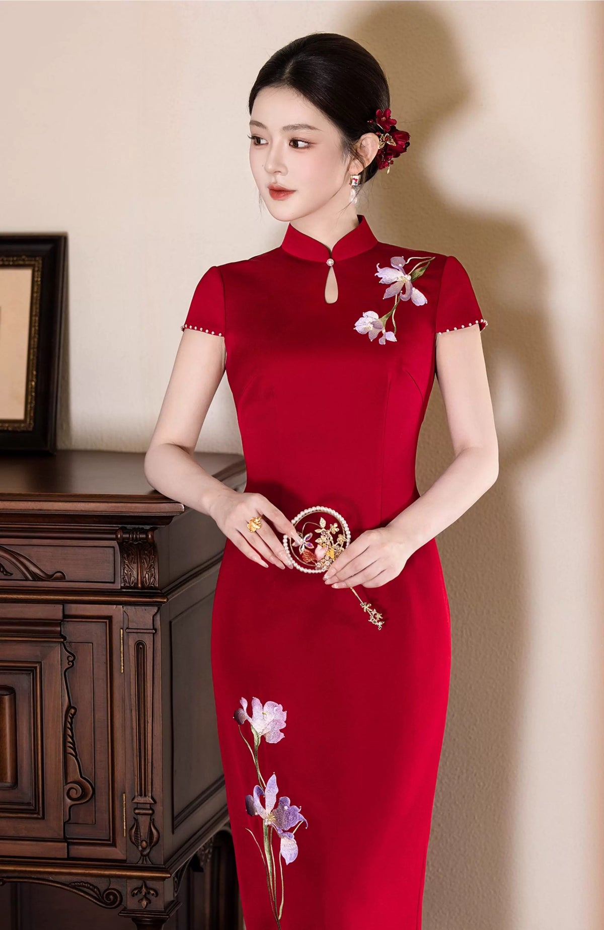 Iris Red Bridal Cheongsam — Three-quarter view holding a round floral accessory