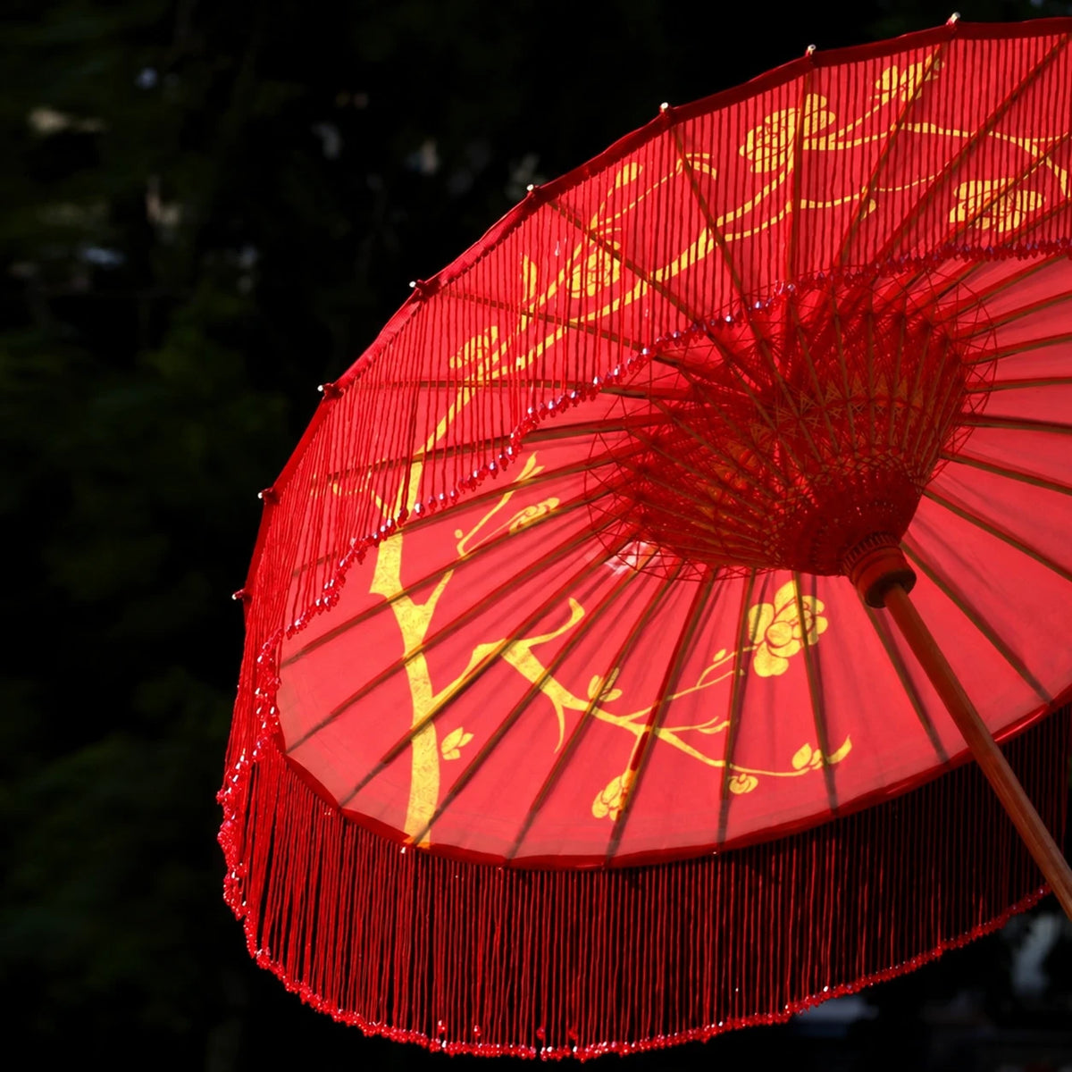 Red oil-paper parasol showing gold-coloured motifs and tassel fringe