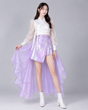 Model holding the lavender layered back skirt to show its sheer ruffled edge, paired with the white top and asymmetric mini skirt.