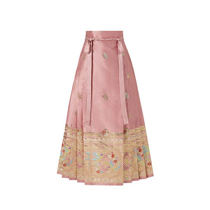 Pink magpie mamian skirt with small woven motifs, waist ties and an ornate gold-tone hem border