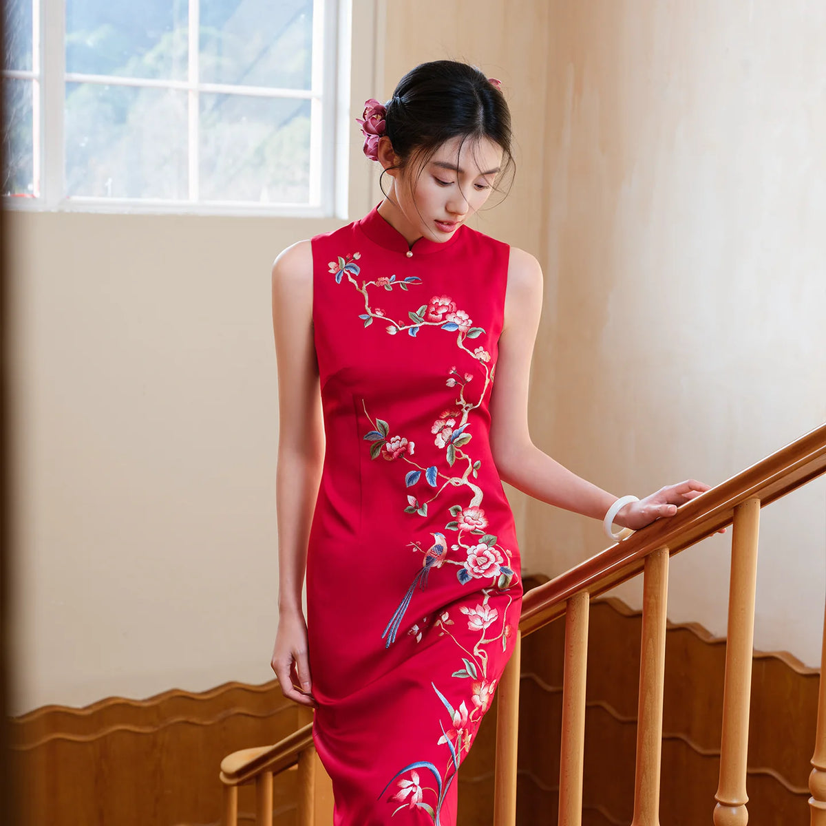 Red embroidered bridal qipao worn beside a staircase