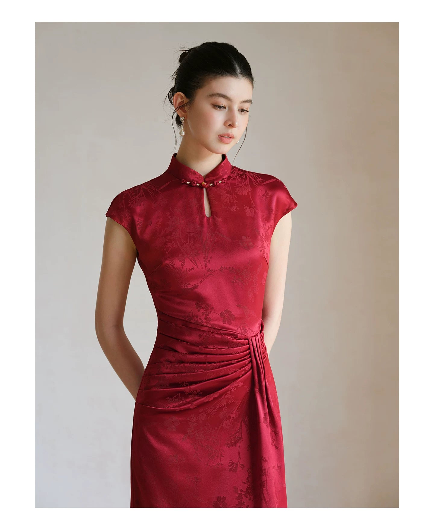 Front styling view of the Ruby Red acetate jacquard pleated qipao dress, with acetate jacquard, sculpted pleats and elegant Chinese dress silhouette.