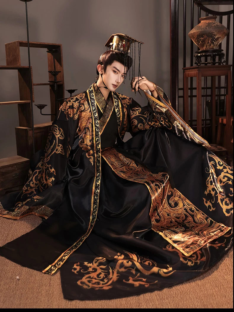 Seated view of a black and gold emperor Hanfu costume with wide sleeves and a trailing patterned hem